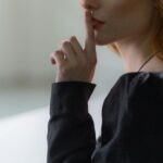 kobieta przykładająca palec do ust w geście uciszania