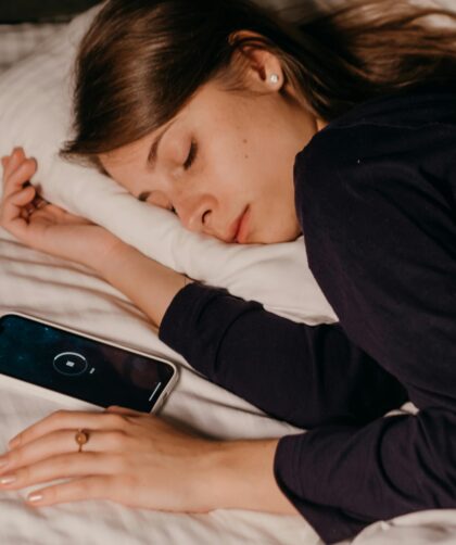 śpiąca kobieta i leżący obok smartfon z włączoną funkcją drzemki