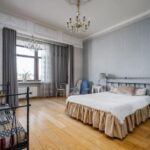 Okno z dwiema warstwami zasłon w eleganckiej sypialni z łóżkiem