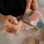 Dłonie malujące pędzlem kolorowy wzór na ceramicznym kubku