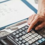 kobieca dłoń wciskająca przycisk na kalkulatorze