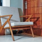 Fotel o drewnianej konstrukcji z szarą tapicerką w stylu mid-century modern