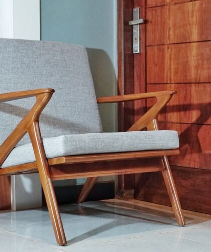 Fotel o drewnianej konstrukcji z szarą tapicerką w stylu mid-century modern