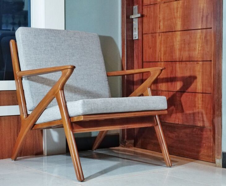 Fotel o drewnianej konstrukcji z szarą tapicerką w stylu mid-century modern