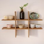 Drewniany organizer ścienny z ceramicznymi naczyniami i szklaną butelką z gałązką