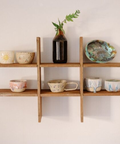 Drewniany organizer ścienny z ceramicznymi naczyniami i szklaną butelką z gałązką