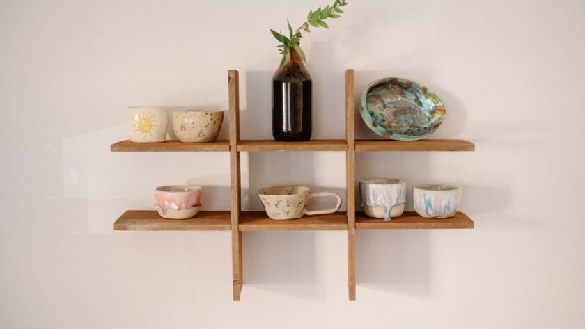 Drewniany organizer ścienny z ceramicznymi naczyniami i szklaną butelką z gałązką