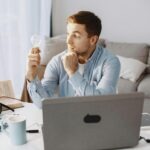 mężczyzna patrzący na trzymaną w ręku żarówkę