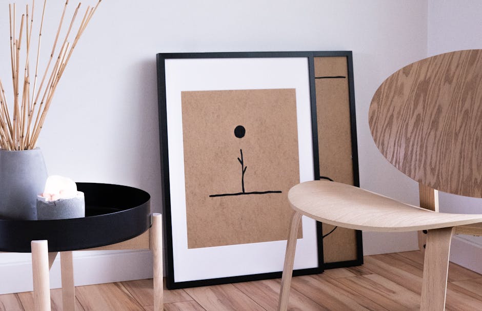 Minimalistyczne wnętrze w stylu Japandi z drewnianym krzesłem i grafiką w ramie.