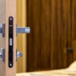 Zamek magnetyczny zamontowany w krawędzi drewnianych drzwi z metalową klamką