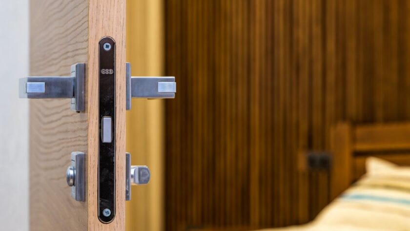 Zamek magnetyczny zamontowany w krawędzi drewnianych drzwi z metalową klamką